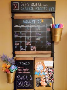 a chalkboard with school calendars on it next to potted plants