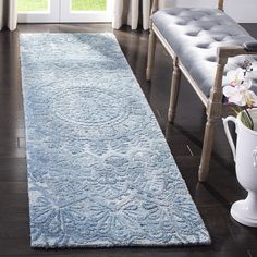 a large blue rug in the middle of a room with a bench and window behind it