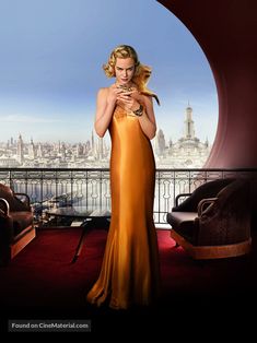 a woman in an orange dress looking at her cell phone while standing on a balcony