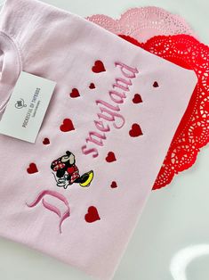 two t - shirts with pink and red hearts on them, one has a minnie mouse embroidered on it