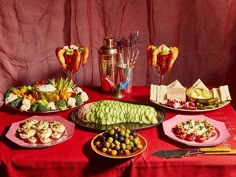 a red table topped with plates and bowls filled with food next to utensils