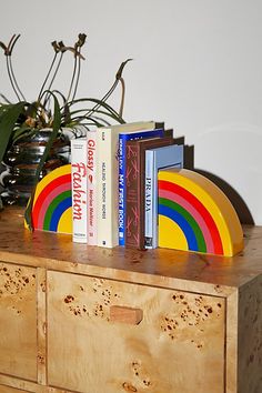 a wooden dresser with books on it and a potted plant in the back ground