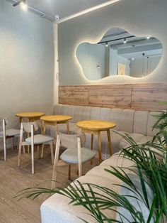 an empty restaurant with wooden tables and white couches in front of a large mirror on the wall