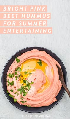 hummus in a black bowl with a spoon on the side and garnished with parsley