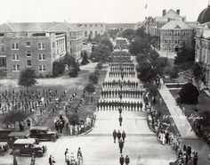 black and white photograph of people walking in front of an old building with many fountains