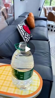 a large bottle of water sitting on top of a table next to a couch and pillows