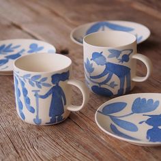 four blue and white coffee cups sitting on top of a wooden table