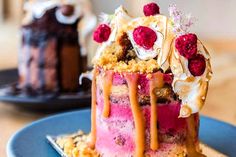 a piece of cake with icing and raspberries on top sitting on a blue plate