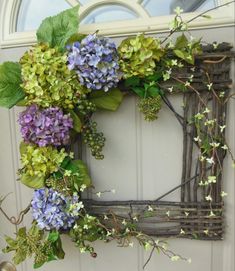 a wreath with purple and green flowers hanging on a door