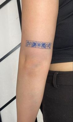 a woman's arm with a tattoo on it that has blue flowers and leaves