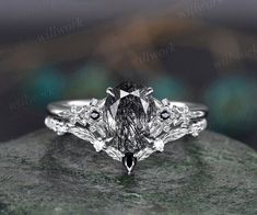 an engagement ring is shown on top of a rock, with the center stone surrounded by smaller stones