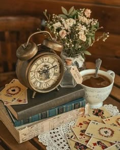 an old fashioned alarm clock sitting on top of a book next to a cup of coffee