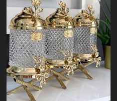 three glass jars with gold decoration on them