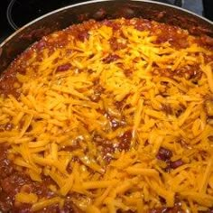 a pizza covered in cheese and chili sitting on top of a stove