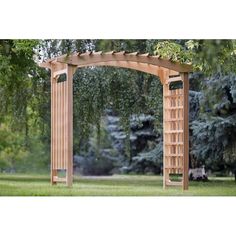 a wooden arbor in the middle of a grassy area with trees and bushes behind it