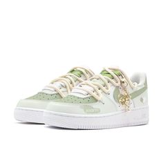 the nike air force 1 low is in white and green with a gold charm on the side