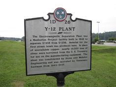 a sign in front of a grassy field with trees and bushes behind it that reads, y - 12 plant