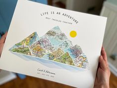 a person holding up a card with a map on it that says life is an adventure