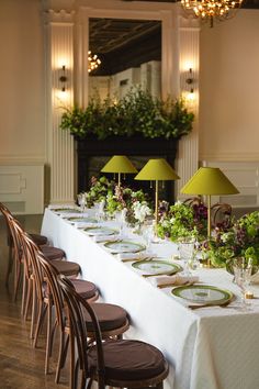 a long table is set with place settings and green lamps