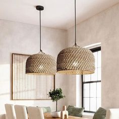 a dining room table with white chairs and two hanging lights above it, in front of a large window