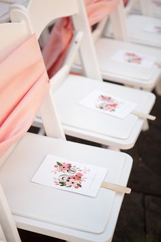 there are four white chairs with pink and red flowers on the seat covers, one is empty