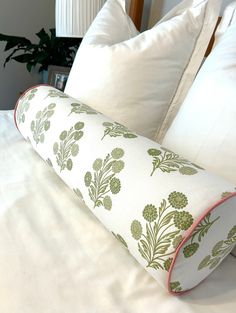 a white bed topped with pillows next to a wooden headboard