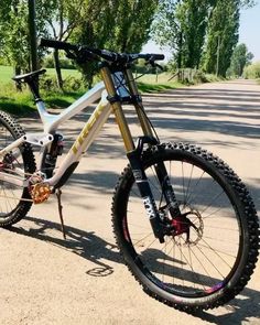 a white and yellow bike parked on the side of a road in front of trees