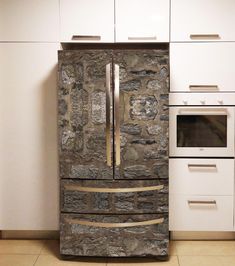 a stone refrigerator in a kitchen next to a stove and cabinets with white cupboards