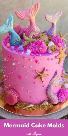 a pink cake with mermaid decorations on it