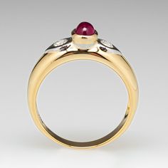 This lovely ring is centered with one (1) oval cabochon cut natural ruby set into a bezel. The shoulders are each accented with one (1), flush set, round brilliant cut diamond. The ring measures 6.7mm at the top, rises 6.8mm above the finger, tapering to 3.1mm wide and 0.8mm thick at the base of the shank. This ring is currently a size 8.5. Elegant Ruby Ring With Bezel Setting, Luxury Ruby And Diamond Oval Cabochon Ring, Luxury Ruby Ring With Oval Cabochon Diamond, Elegant Ruby Ring With Oval Diamond, Oval Cabochon Ruby And Diamond Ring, Formal Ruby Ring With Diamond And Oval Cabochon Shape, Formal Ruby Ring With Oval Cabochon Center Stone, Formal Ruby Ring With Oval Cabochon, Formal Oval Cabochon Ruby Ring With Diamond