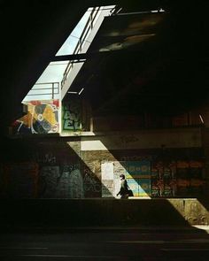 a person walking down a street under a bridge with graffiti on the side of it