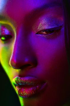 a woman's face is lit up with neon colors and has her eyes closed