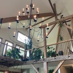 a chandelier hanging from the ceiling in a room with wooden beams and windows