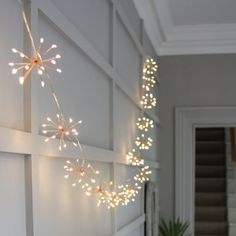 a white wall with lights hanging from it's sides and a potted plant next to it