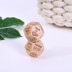 two wooden dices sitting on top of each other next to a green leaf and white towel