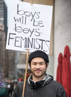 a man holding a sign that says boys will be boys feminists