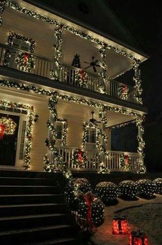 christmas lights decorate the front of a house with candles and wreaths on the porch