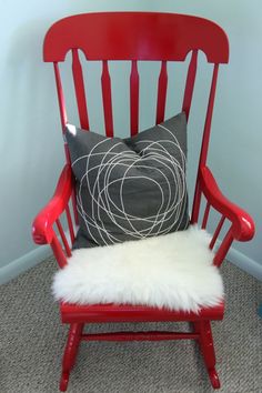 a red chair with a pillow on top of it and a white fur rug in front of it