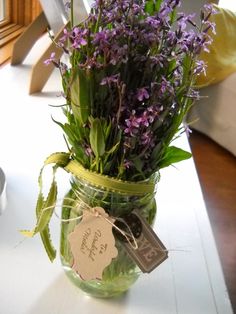 a jar filled with purple flowers sitting on top of a table