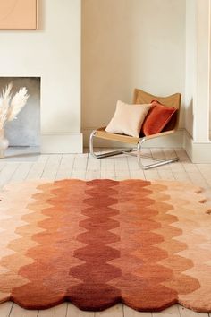 a living room with a chair and rug on the floor in front of a fire place