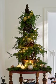 a christmas tree with lights and ornaments on the top is sitting on a small table