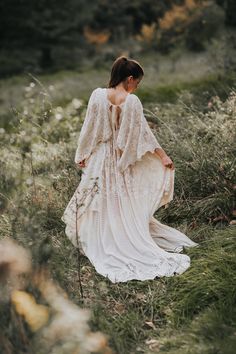 a woman in a white dress walking through tall grass