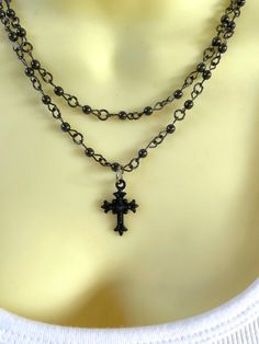 Without a doubt, this necklace is going to gather compliment after compliment for you! The double strand black beaded chains are tiny hematite beads, and the cross has tons of sparkle and charm, plus a little dark mojo I super love! I have other necklaces in similar styles, both choker length like this as well as longer chains - look for them in the shop! Measures about 17 & 18 inches (short and long chain) but can easily be adjusted for you in the shop to any preferred length! Cheap Beaded Cross Necklaces, Cheap Black Cross Jewelry, Thirteen Movie Cross Necklace, Cheap Black Cross Necklace, Cross Jewelry Goth, Beeded Cross Necklace, Summer Goth Necklace, Rosary Necklace Black Gold, Multi Chain Choker Necklace With Cross