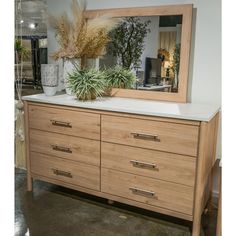 a wooden dresser with a mirror and plants on top