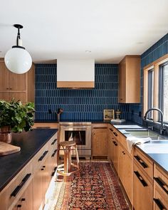 a kitchen with wooden cabinets and blue tile backsplash, an area rug on the floor