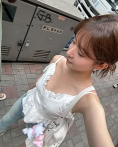 a woman in a white dress standing next to a parking meter with her hand on the ground