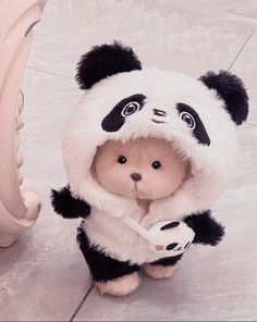 a teddy bear dressed in a panda suit and holding a knife with its paws on the ground