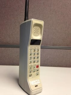 an old style phone sitting on top of a white table next to a gray wall