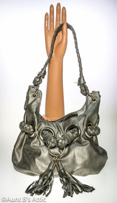 "80's to the Max!, vintage Bay Studio silver faux leather bucket style bag. Large silver metal rings hold the 18\" long braided handle. Another braided strap is woven through large silver metal rings in the front, and accented with 2 large tassels. The bag is lined with a leopard print cloth lining, and has 1 zippered pocket, and one open pocket. Snap strap closure. Bag sits on an oval base thats 7 1/2\" x 4 1/2\". Total height including strap-12\" Bag is in very good condition, and clean. *All Silver Leather Shoulder Bag With Hardware, Silver Shoulder Bag With Hardware For Everyday Use, Silver Bucket Bag With Silver-tone Hardware For Everyday Use, Silver Bucket Bag With Silver-tone Hardware, Large Tassels, Metallic Handbags, Silver Handbag, Silver Bags, Vintage Leather Bag