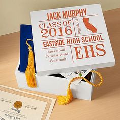 a white box with a yellow tassel on top of it and a certificate in front of it